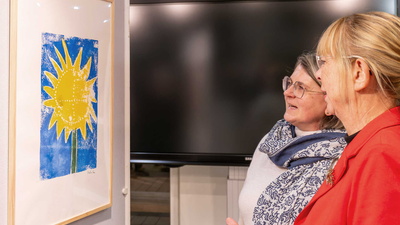 Zwei Frauen betrachten einen bunten Linoldruck