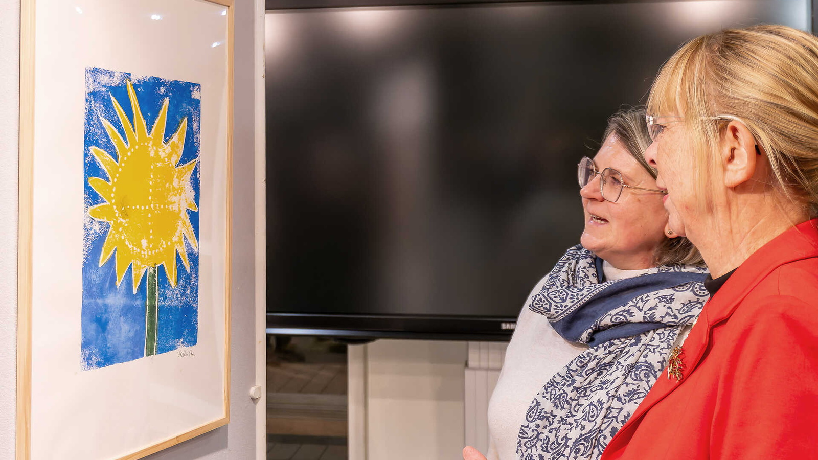 Zwei Frauen betrachten einen bunten Linoldruck